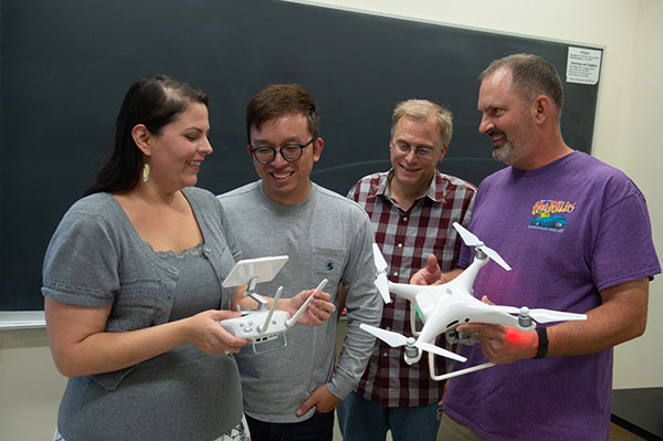 3 Students and Teacher Holding a Drone in FAA Remote Pilot License Class